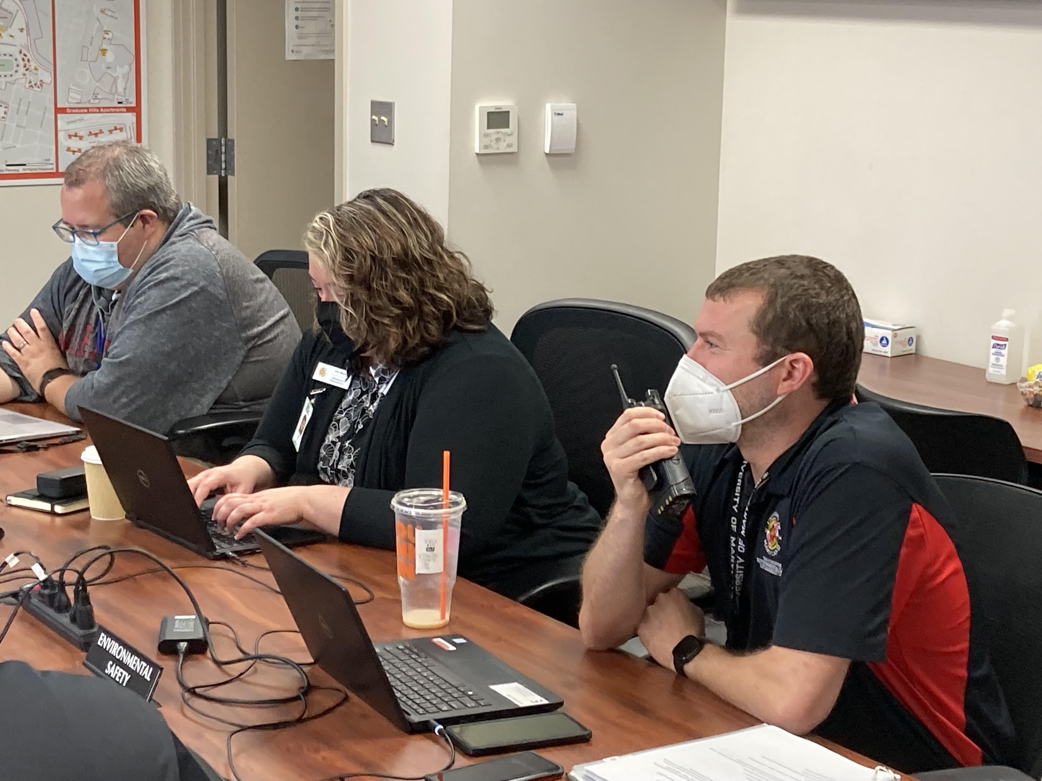 Three Office of Emergency Management and Business Center staff in masks sitting at a conference table